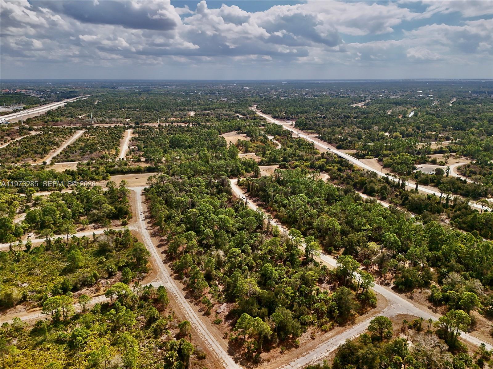 An aerial view shows a network of paved roads winding through a wooded, undeveloped landscape — 0 IRONSIDE ST, North Port FL 34288, NORTH PORT, FL