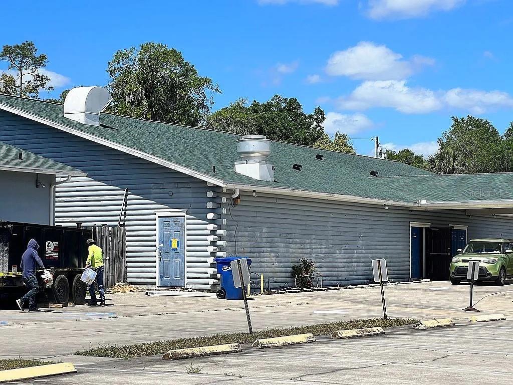 A blue log-style building with a green shingled roof and a dumpster in the parking lot — 301 W BLUE SPRINGS AVENUE, ORANGE CITY, FL