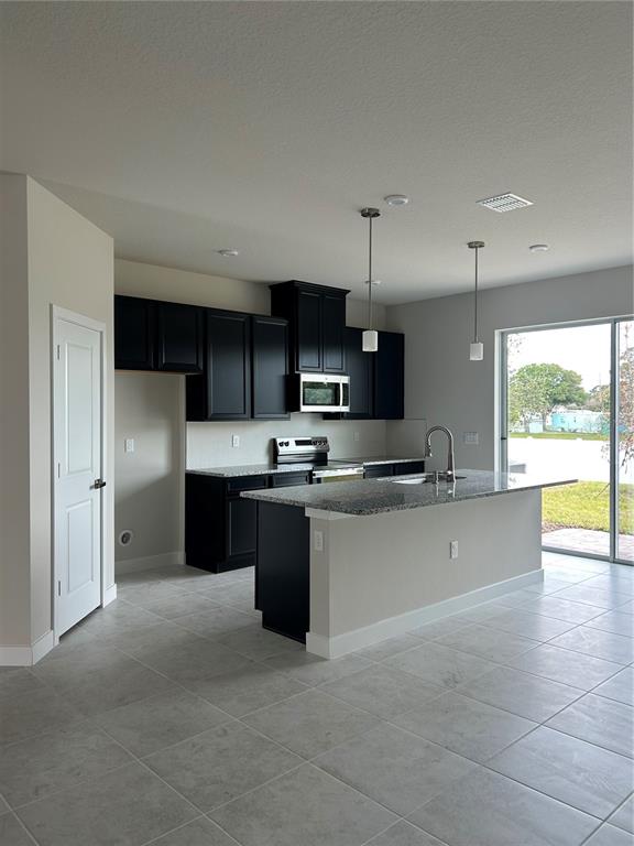 A kitchen features black cabinets, granite countertops, a center island, and tile flooring — 1838 KENDALL POINTE PLACE, MELBOURNE, FL