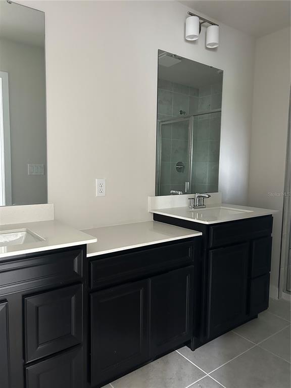 A bathroom features a double vanity with black cabinets, white countertops, and two mirrors — 1838 KENDALL POINTE PLACE, MELBOURNE, FL