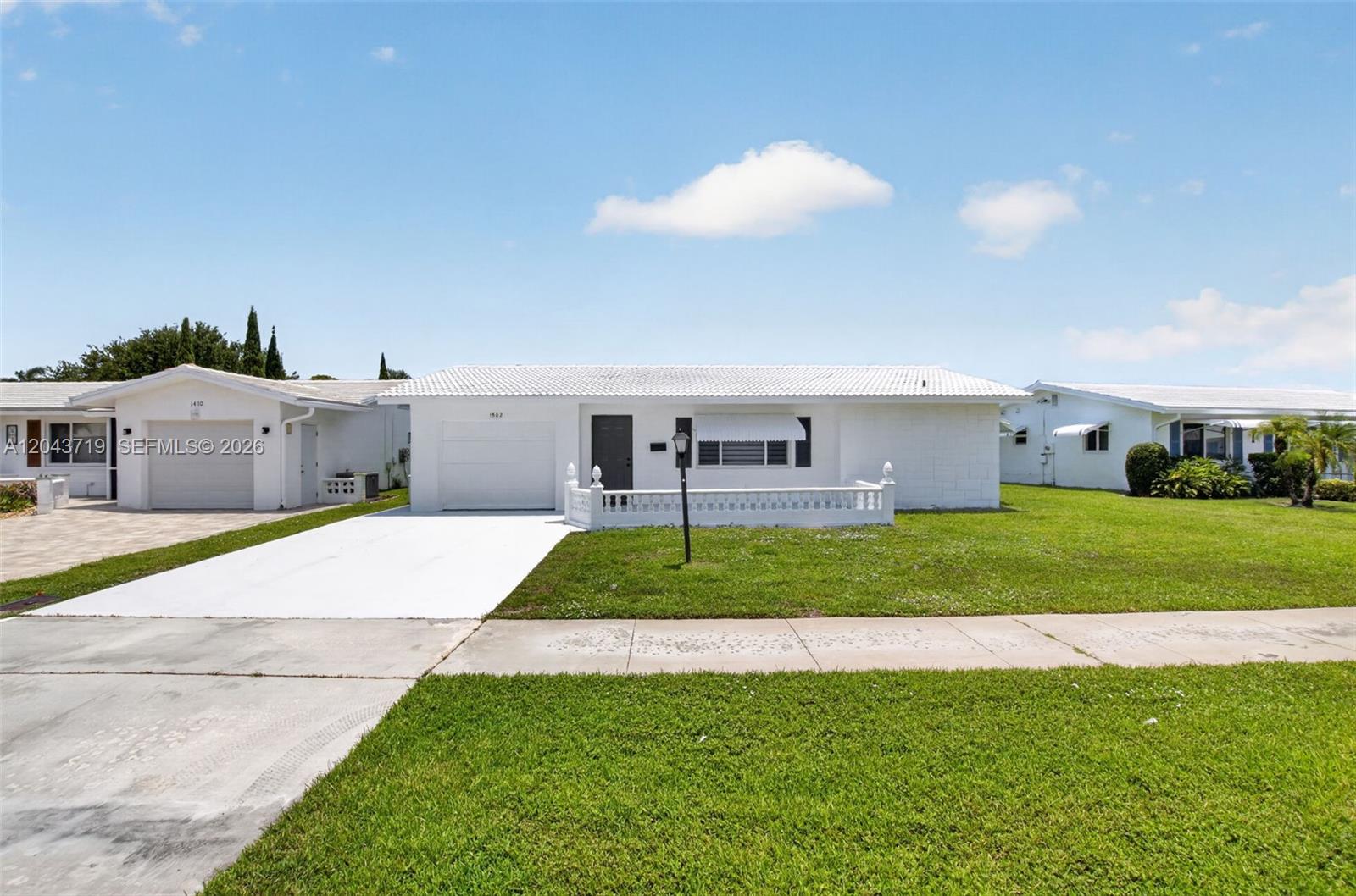 A white single-story house with a tiled roof, a garage, and a front lawn — 1502 SW 17th Ave, Boynton Beach FL 33426, BOYNTON BEACH, FL