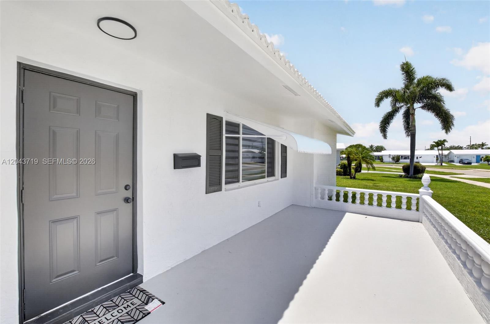 A white house exterior features a gray front door, a porch, and a palm tree — 1502 SW 17th Ave, Boynton Beach FL 33426, BOYNTON BEACH, FL