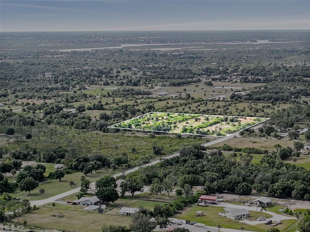 An aerial view shows a rectangular plot of land outlined in white amidst rural surroundings — 6211 GROVE BOULEVARD, PUNTA GORDA, FL