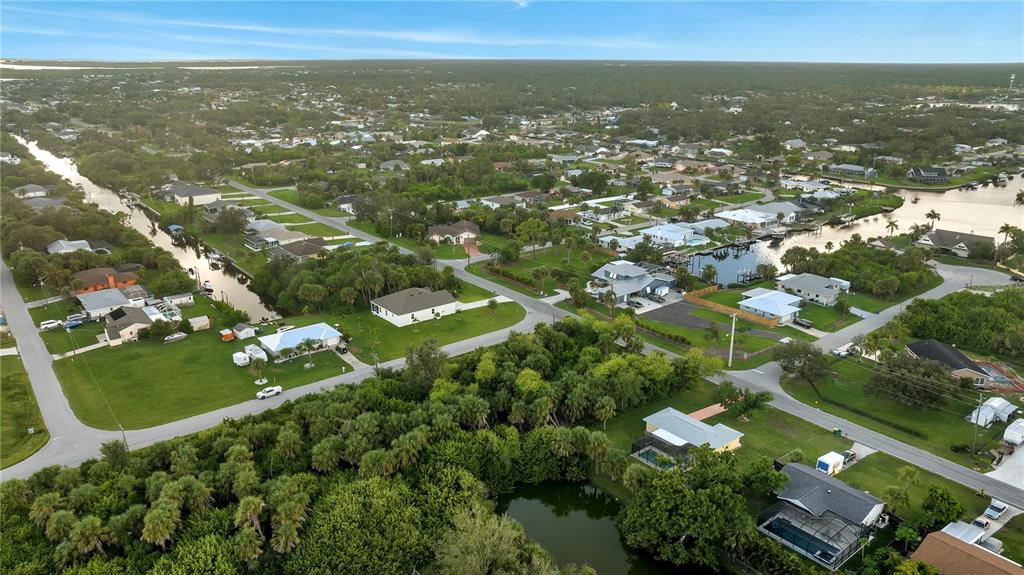 An aerial view shows a suburban neighborhood with houses, canals, and dense vegetation — 5016 SILVER BELL DRIVE, PORT CHARLOTTE, FL