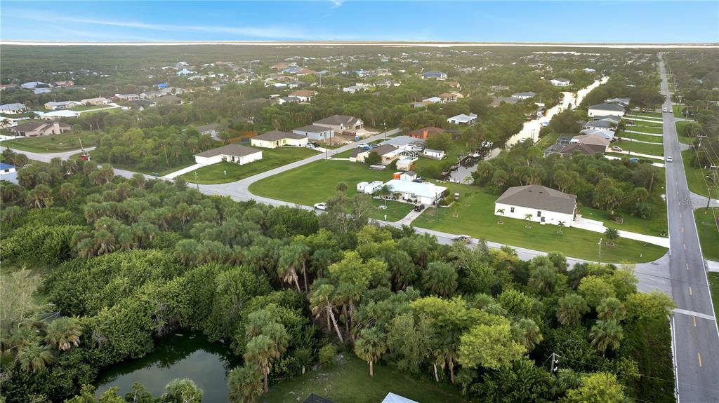 An aerial view shows houses, a canal, and dense vegetation in a suburban neighborhood — 5016 SILVER BELL DRIVE, PORT CHARLOTTE, FL