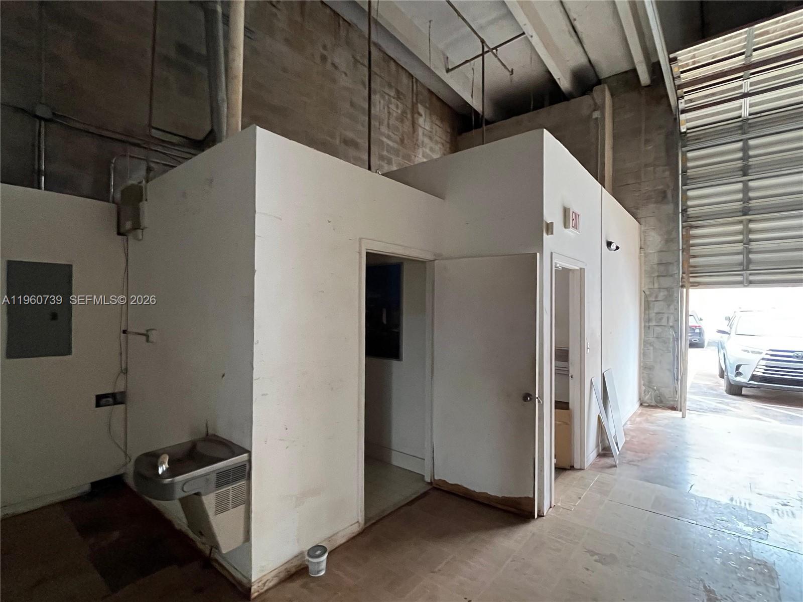 A warehouse interior features a small office structure with a water fountain and roll-up door — 12361 SW 128th Ct # 203, Miami FL 33186, MIAMI, FL