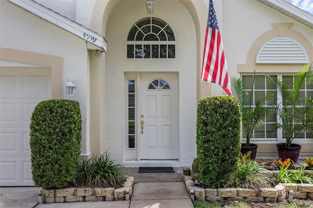 The exterior of a house features a white front door, arched window, and American flag — 4919 JETTON DRIVE, ORLANDO, FL