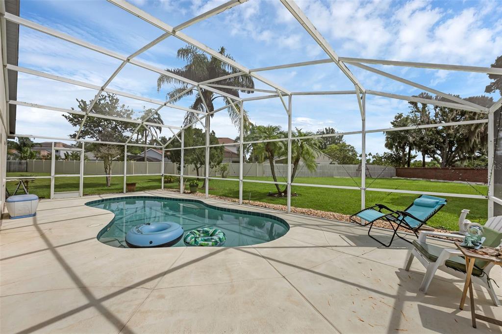 A screened-in patio features a swimming pool, lounge chairs, and a large grassy backyard — 4919 JETTON DRIVE, ORLANDO, FL