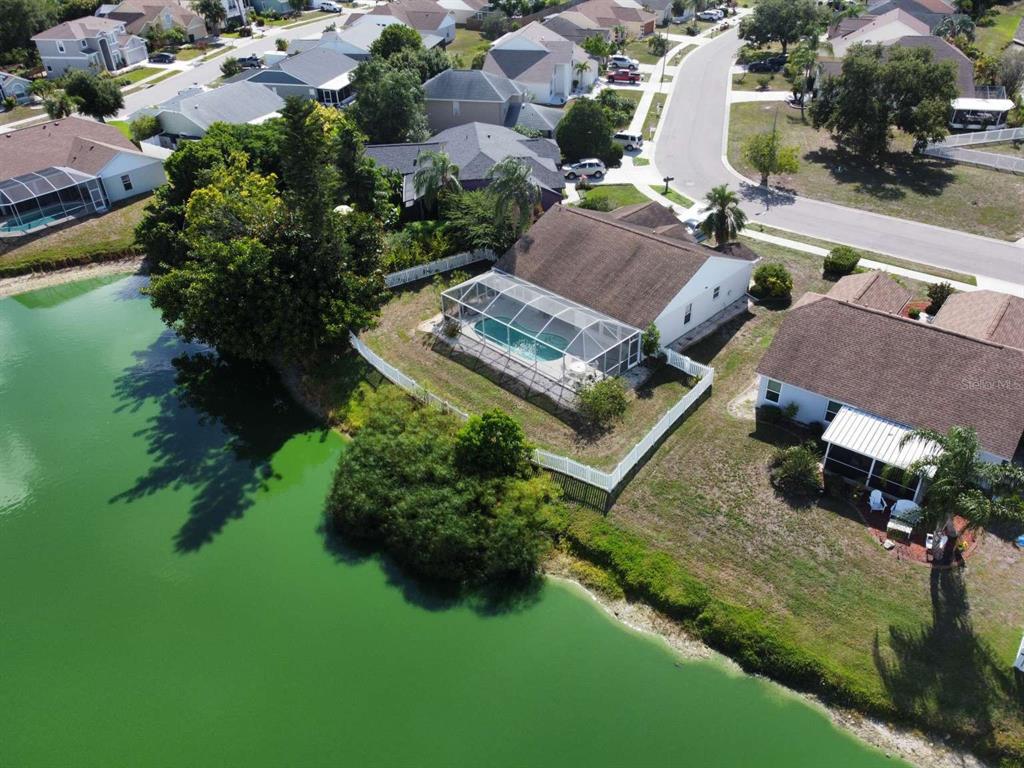 An aerial view shows a house with a screened-in pool beside a green pond — 4826 11TH AVENUE CIRCLE E, BRADENTON, FL