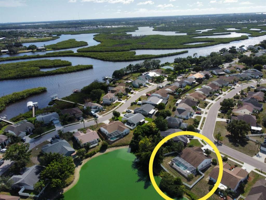 An aerial view shows a residential neighborhood with a house circled near a small pond — 4826 11TH AVENUE CIRCLE E, BRADENTON, FL