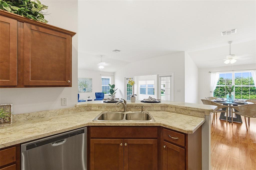 A kitchen sink and dishwasher are set into a beige countertop with wood cabinets — 3258 HOLLEY TERRACE, THE VILLAGES, FL