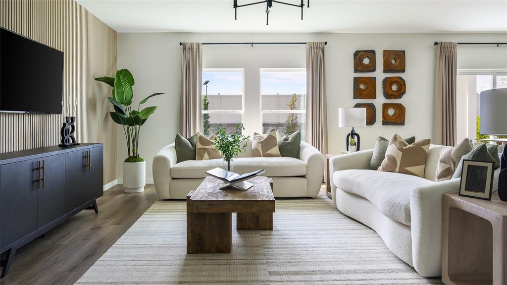 A living room features two white sofas, a wooden coffee table, and a slatted wall — 33639 NOBLE CREEK PLACE, DADE CITY, FL