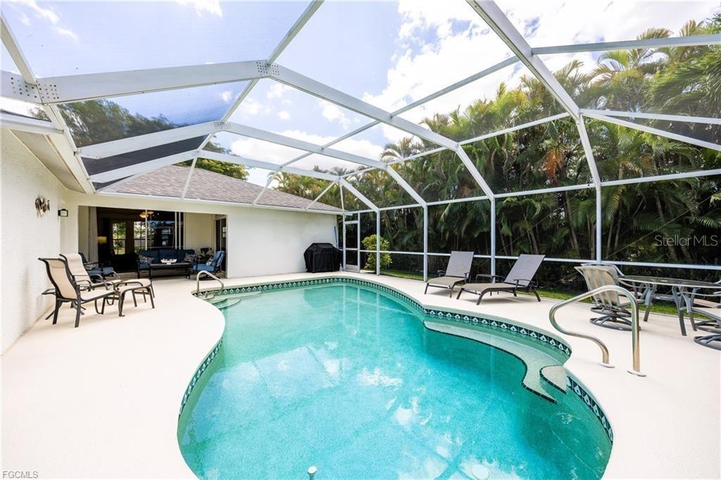 A swimming pool with a screened enclosure and patio furniture sits in a backyard — 4522 SW 1ST AVENUE, CAPE CORAL, FL