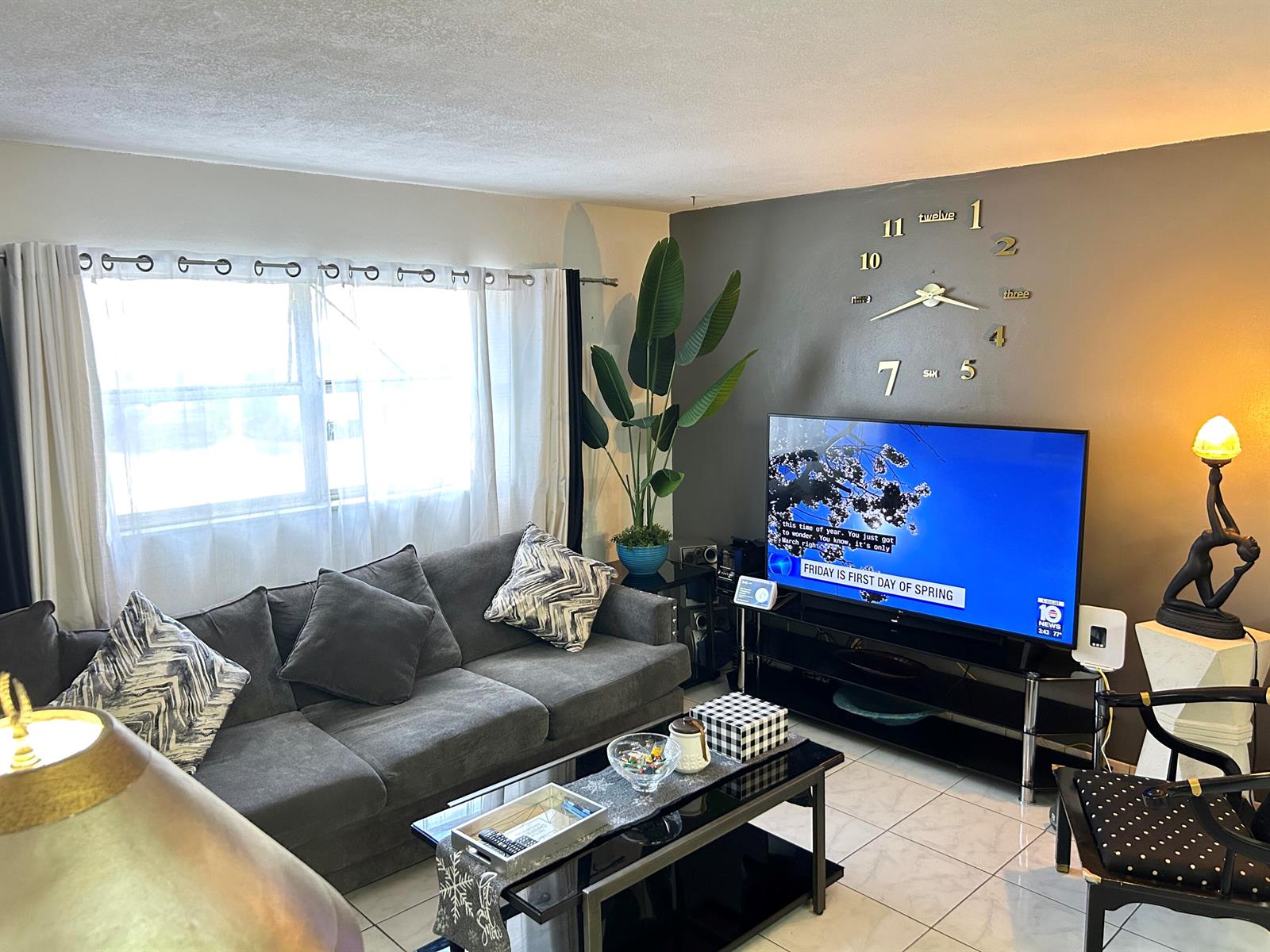 A living room features a grey sofa, a glass coffee table, and a wall clock — 515 S Crescent Drive # 107, Hollywood FL 33021, HOLLYWOOD, FL