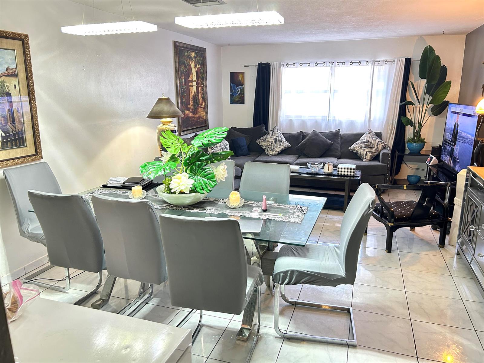 A dining area with a glass table and grey chairs sits before a living room — 515 S Crescent Drive # 107, Hollywood FL 33021, HOLLYWOOD, FL
