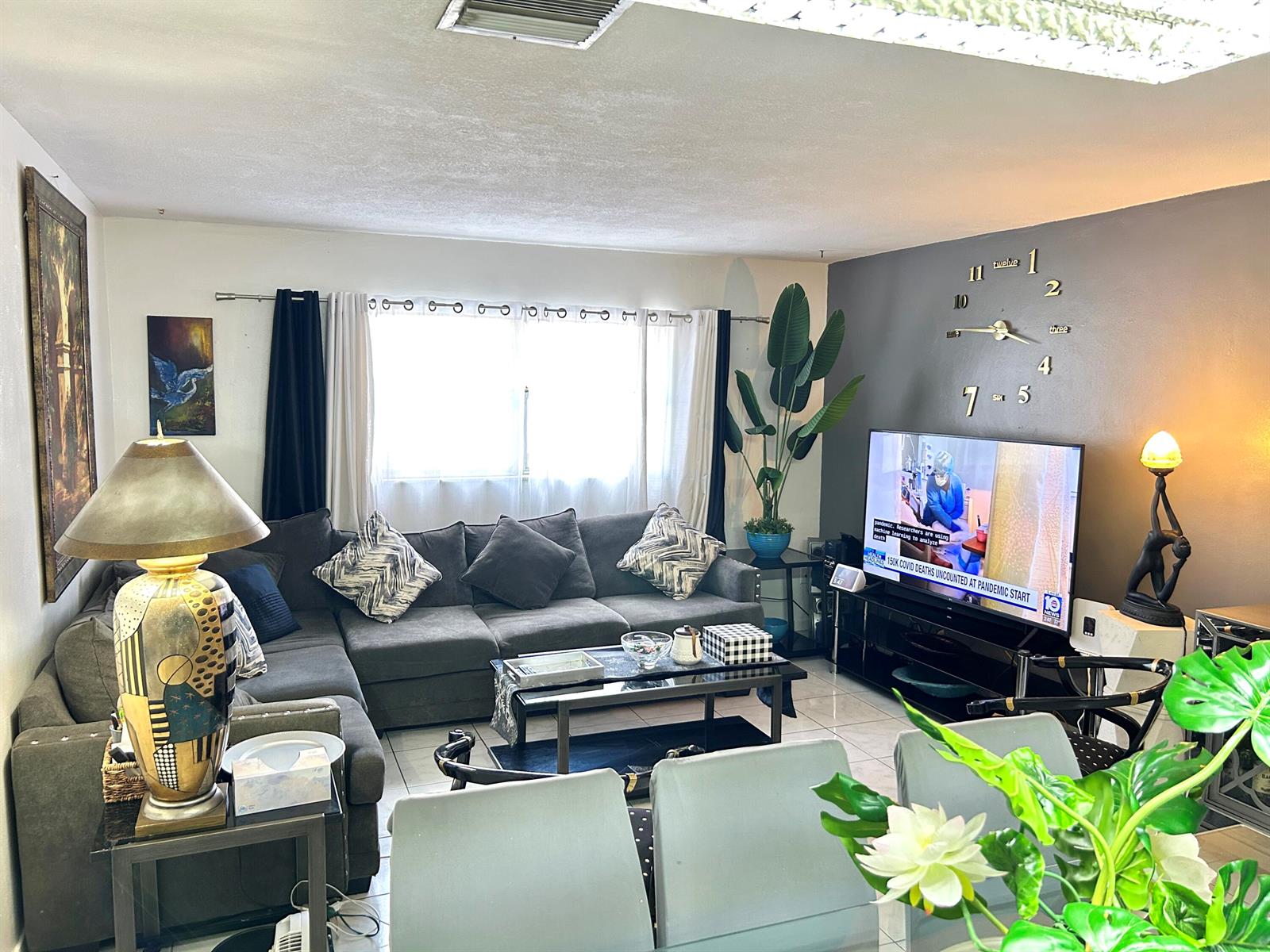 A living room features a grey sectional sofa, a television, and a large wall clock — 515 S Crescent Drive # 107, Hollywood FL 33021, HOLLYWOOD, FL