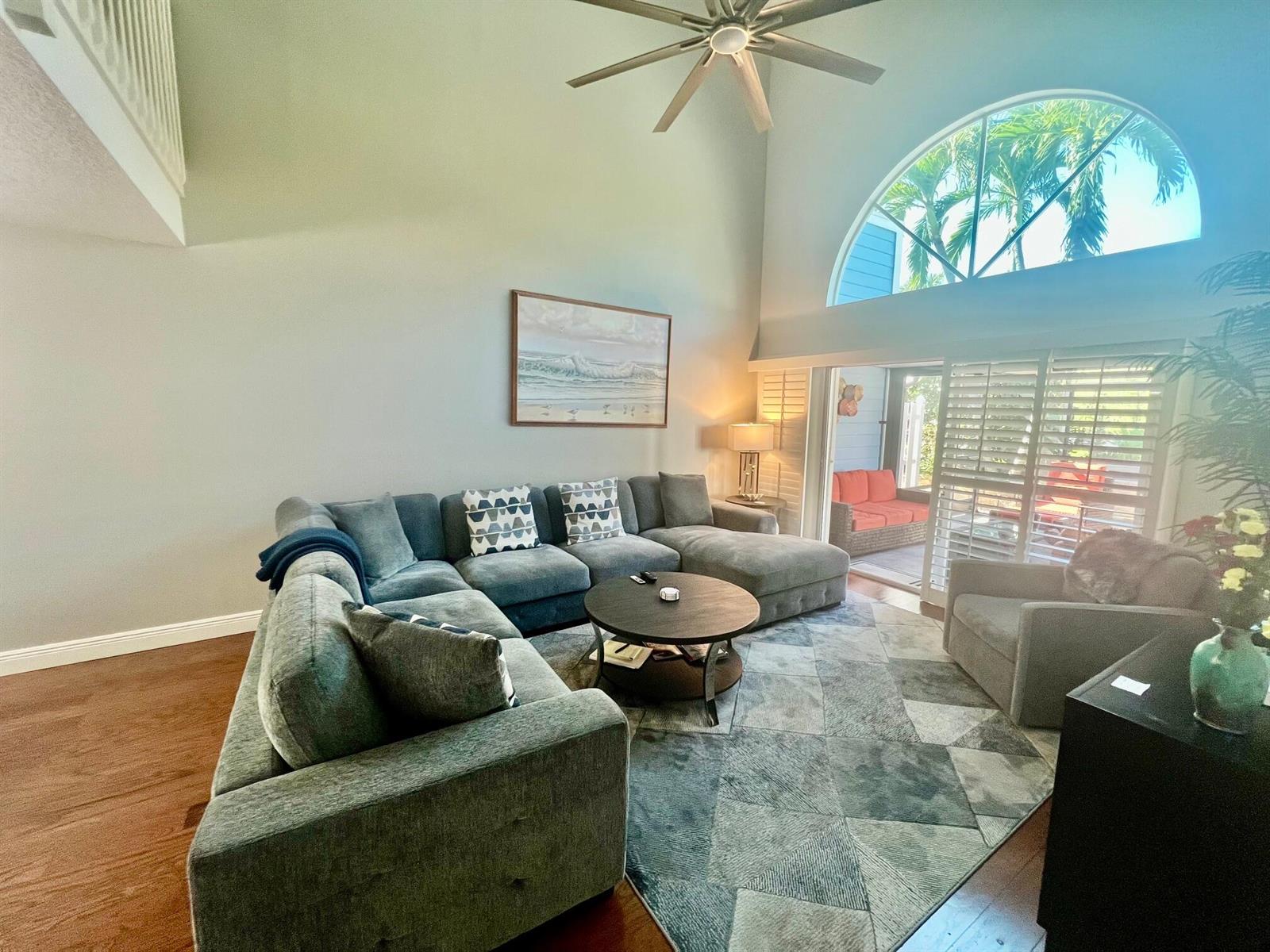 A living room features a large sectional sofa, a round coffee table, and vaulted ceilings — 1209 Ocean Dunes Circle, Jupiter FL 33477, JUPITER, FL