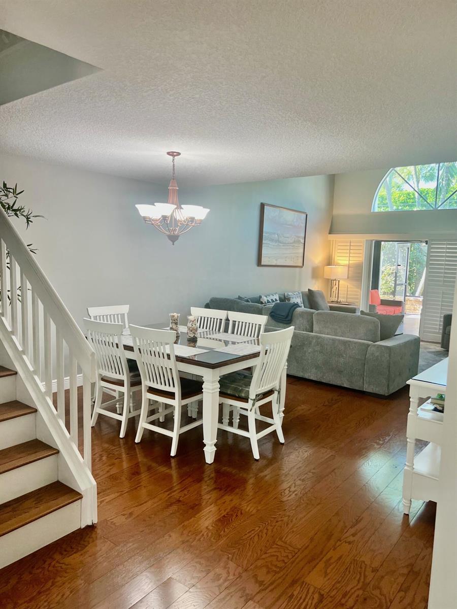 A dining area with a white table and chairs sits next to a living room — 1209 Ocean Dunes Circle, Jupiter FL 33477, JUPITER, FL