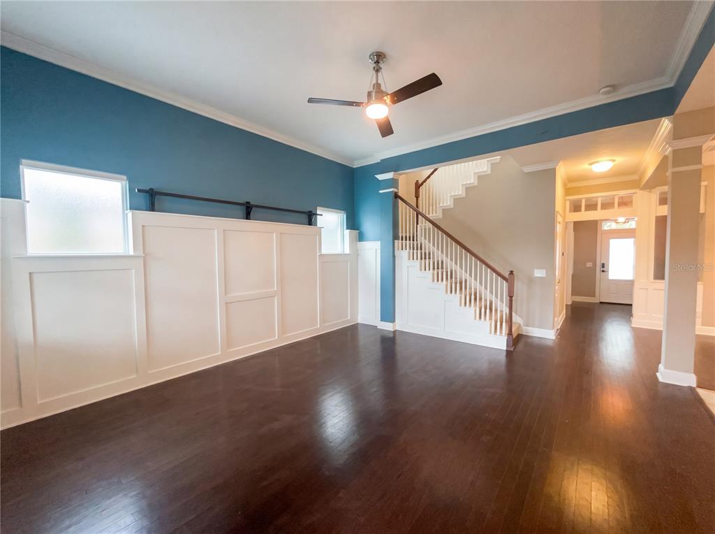 A living room features dark hardwood floors, blue accent walls, white wainscoting, and a staircase — 1338 UNION CLUB DRIVE, WINTER GARDEN, FL