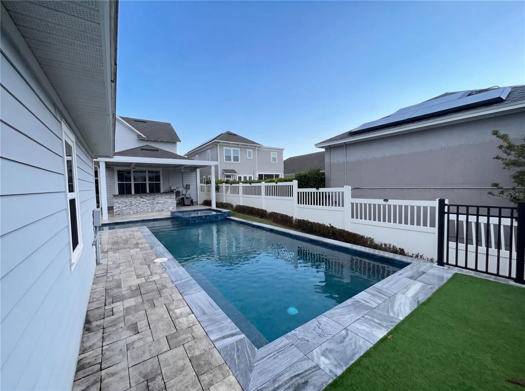 A rectangular swimming pool with a spa sits in a backyard with a stone patio — 1338 UNION CLUB DRIVE, WINTER GARDEN, FL