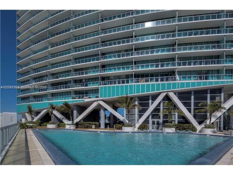 A swimming pool sits in front of a modern high-rise building with glass balconies — 888 Biscayne Blvd # 2911, Miami FL 33132, MIAMI, FL