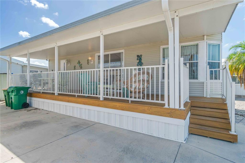 A mobile home exterior features a covered wooden deck with white railings and stairs — 1475 FLAMINGO DRIVE UNIT 195, ENGLEWOOD, FL