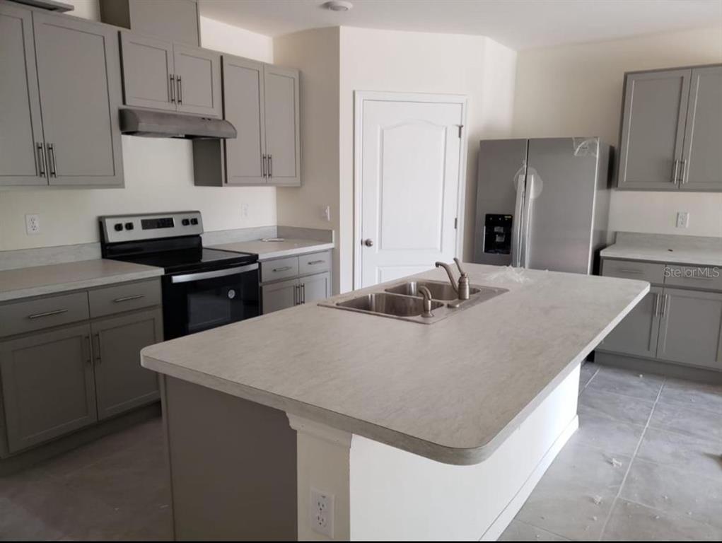 A kitchen features gray cabinets, stainless steel appliances, a center island, and light-colored countertops — 713 FULMAR COURT, POINCIANA, FL