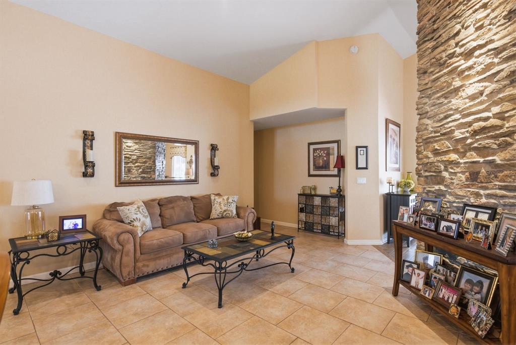 A living room features a stone fireplace, tile flooring, and a brown sofa — 3228 BENTLEY DRIVE, PALM HARBOR, FL