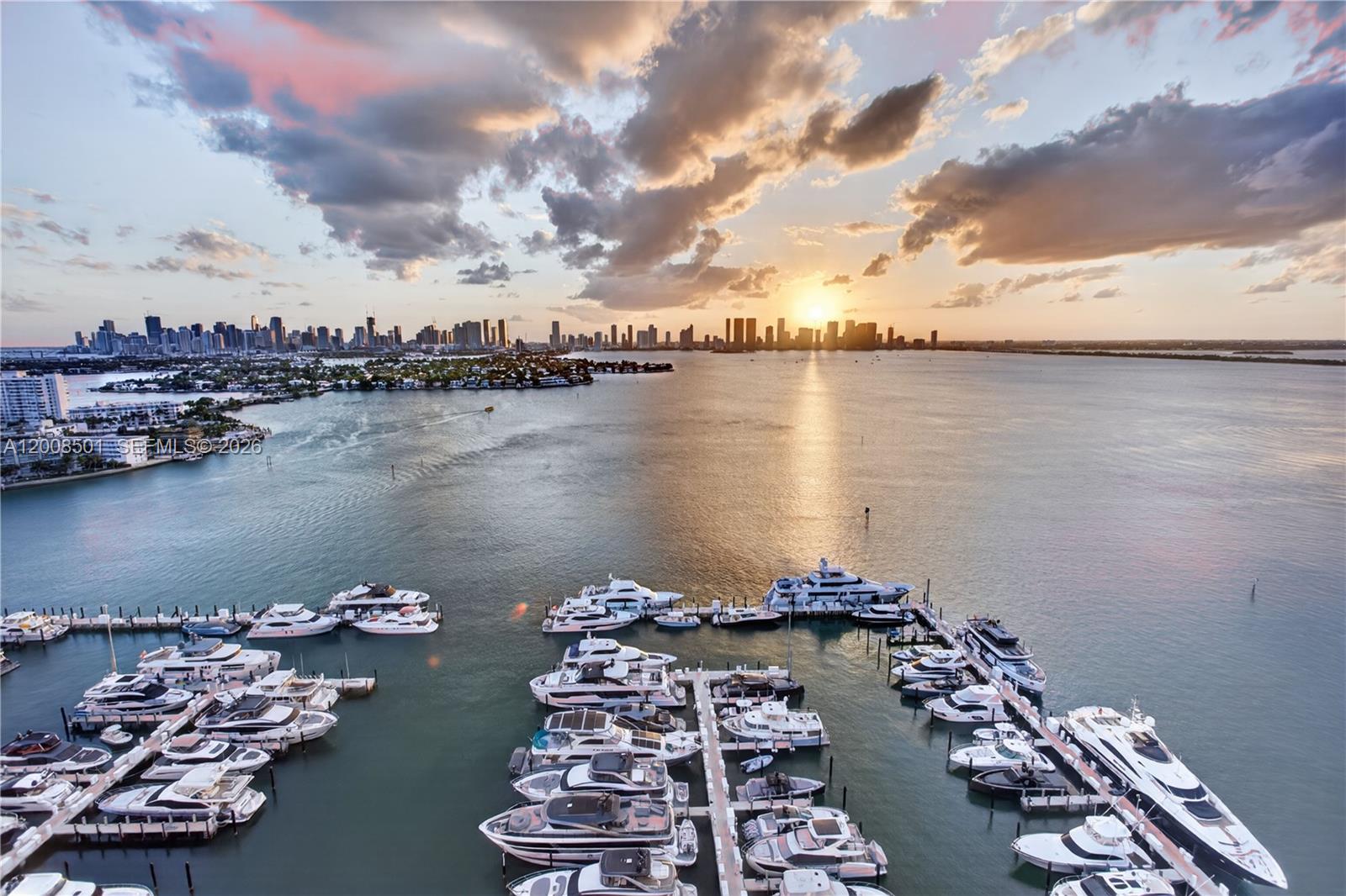 An aerial view shows a marina filled with yachts at sunset near a city skyline — 1900 Sunset Harbour Dr, Miami Beach FL 33139, MIAMI BEACH, FL