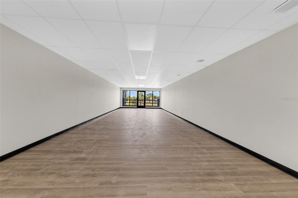 An empty, rectangular commercial space features light wood-look flooring, white walls, and a drop ceiling — 3596 TAMIAMI TRAIL, PORT CHARLOTTE, FL