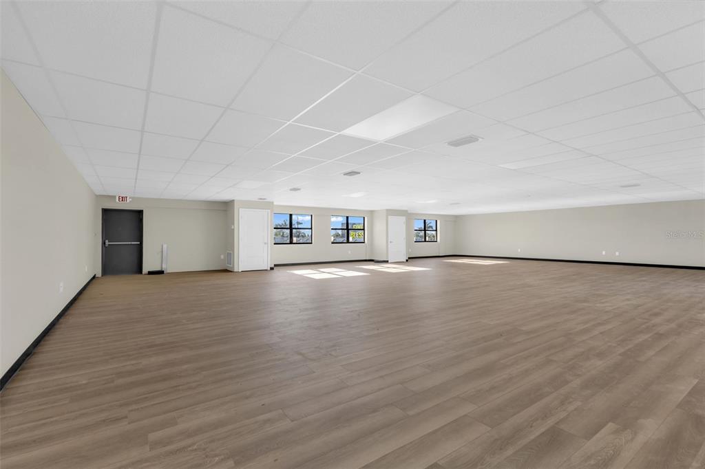 A large, open office space with wood-look flooring, a drop ceiling, and several windows — 3596 TAMIAMI TRAIL, PORT CHARLOTTE, FL