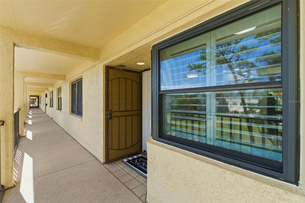 An exterior walkway leads to the entrance of a residential unit with a screen door — 5775 PARK STREET N UNIT 311, ST PETERSBURG, FL