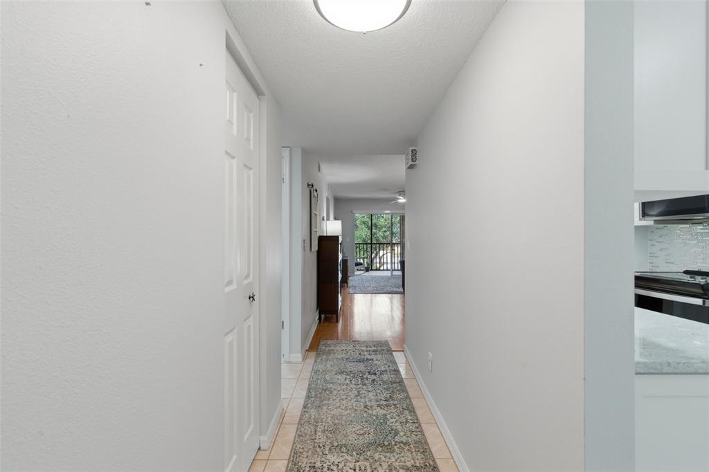A hallway with tile flooring and a runner rug leads toward a living area — 5775 PARK STREET N UNIT 311, ST PETERSBURG, FL