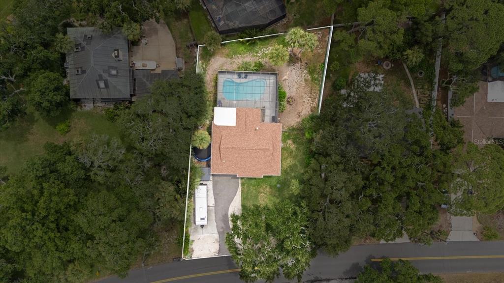 An aerial view shows a house with a pool, screened enclosure, and driveway on a lot — 1410 RIVERSIDE DRIVE, TARPON SPRINGS, FL
