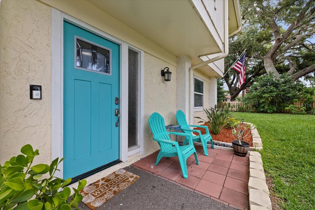 A teal front door and two matching chairs sit on a small brick patio — 1410 RIVERSIDE DRIVE, TARPON SPRINGS, FL