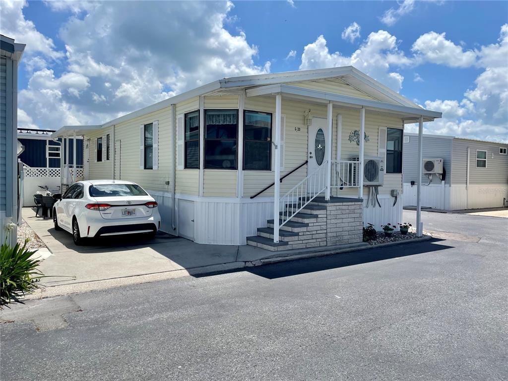 A light yellow mobile home with a front porch, stairs, and a parked white car — 3710 GULF OF MEXICO DRIVE UNIT G20, LONGBOAT KEY, FL