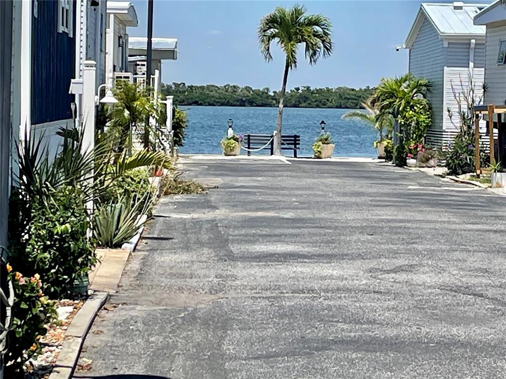 A paved driveway leads toward a waterfront view with a palm tree and a bench — 3710 GULF OF MEXICO DRIVE UNIT G20, LONGBOAT KEY, FL