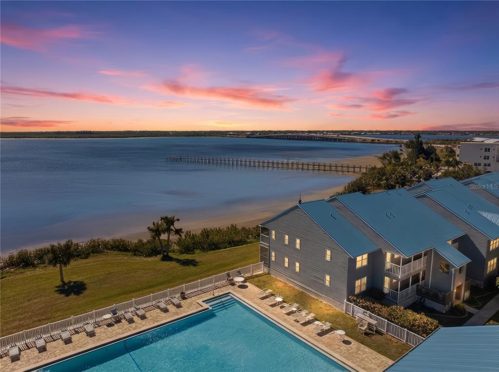 An aerial view of a swimming pool, multi-story buildings, and a pier along the water — 4410 WARREN AVENUE UNIT 108, PORT CHARLOTTE, FL