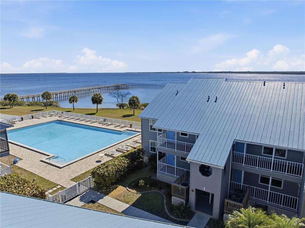 An aerial view shows a multi-story building with a metal roof next to a swimming pool — 4410 WARREN AVENUE UNIT 108, PORT CHARLOTTE, FL