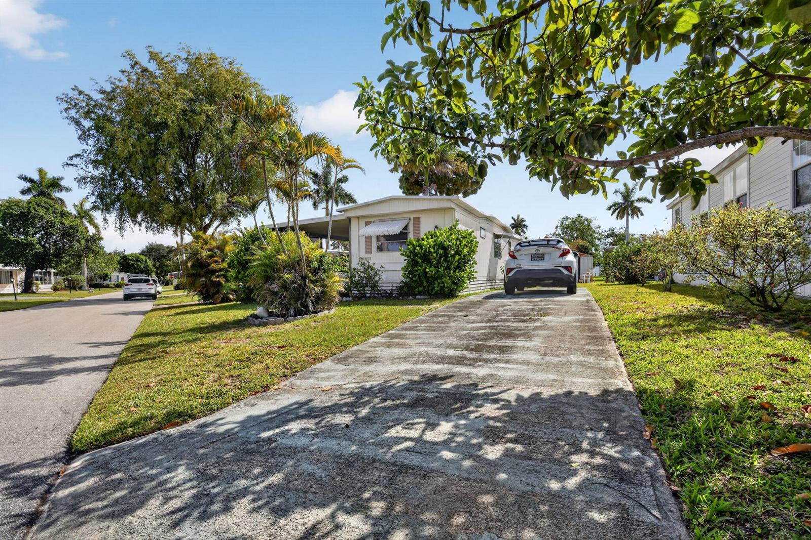 A single-story mobile home with a concrete driveway and a parked car in front — 12375 S Military Trail # 90, Boynton Beach FL 33436, BOYNTON BEACH, FL