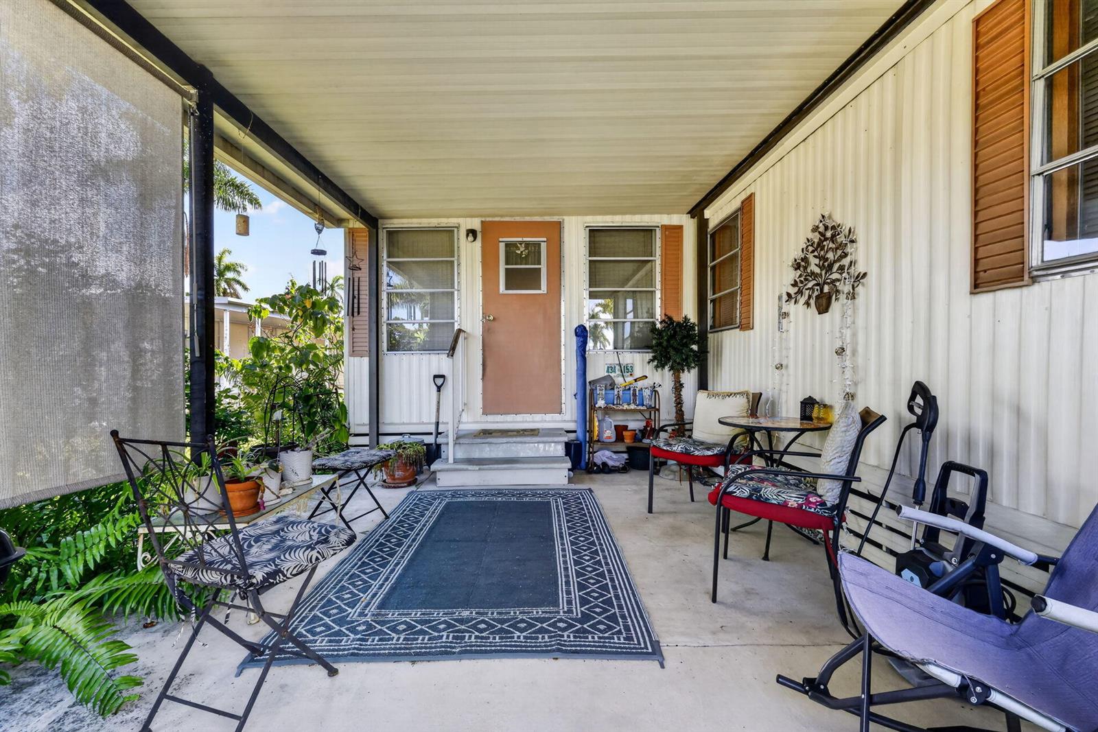 A covered outdoor patio features a concrete floor, a patterned rug, and various seating furniture — 12375 S Military Trail # 90, Boynton Beach FL 33436, BOYNTON BEACH, FL