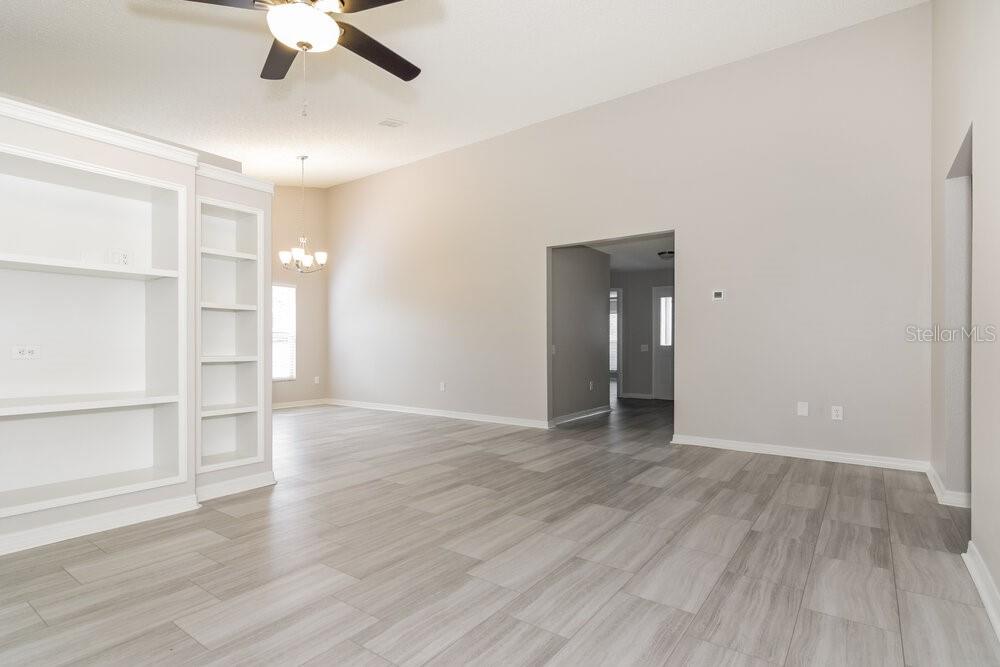 An empty room features light gray wood-look tile flooring, white built-in shelving, and a ceiling fan — 26808 HAVERHILL DRIVE, LUTZ, FL