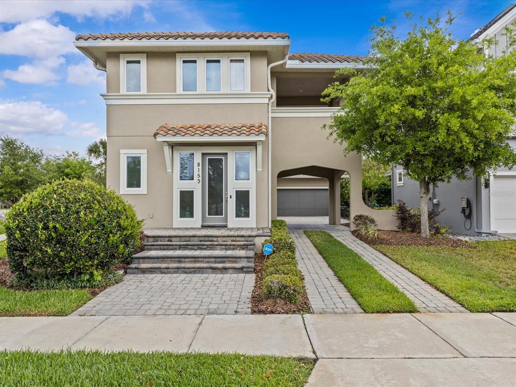 A two-story house with a paved walkway, stone steps, and a covered driveway entrance — 8153 BELLOW STREET, ORLANDO, FL