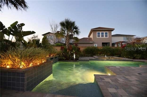 A backyard swimming pool with a raised planter and stone patio at dusk — 8153 BELLOW STREET, ORLANDO, FL