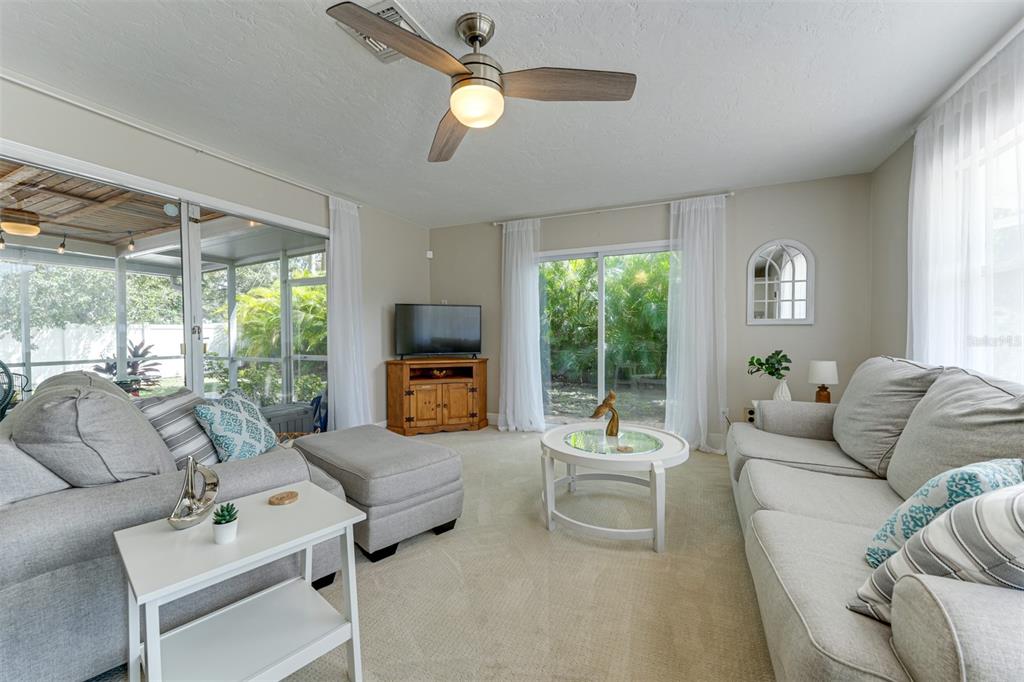 A living room features light gray sofas, a ceiling fan, and sliding glass doors — 2363 MILFORD CIRCLE, SARASOTA, FL