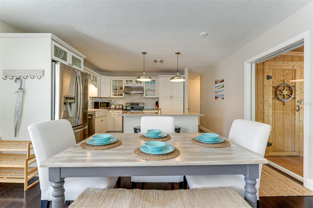 A dining area with a wooden table and white chairs opens into a white kitchen — 2363 MILFORD CIRCLE, SARASOTA, FL