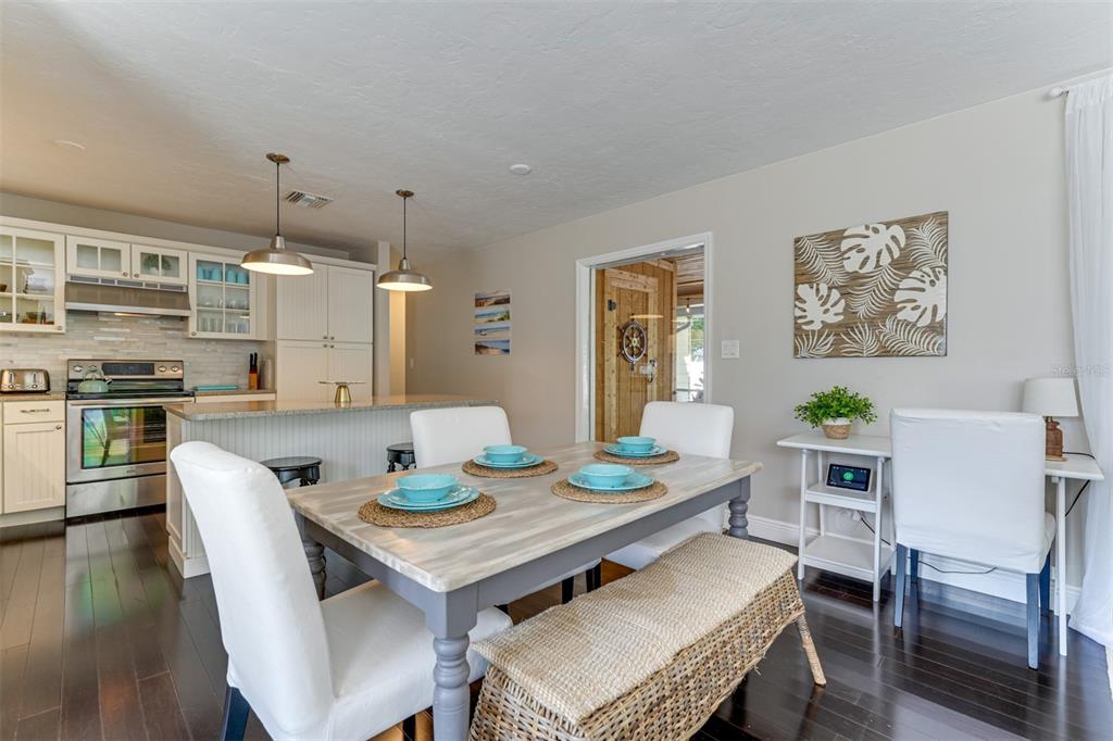 A dining area with a wooden table, chairs, and bench sits adjacent to a kitchen — 2363 MILFORD CIRCLE, SARASOTA, FL