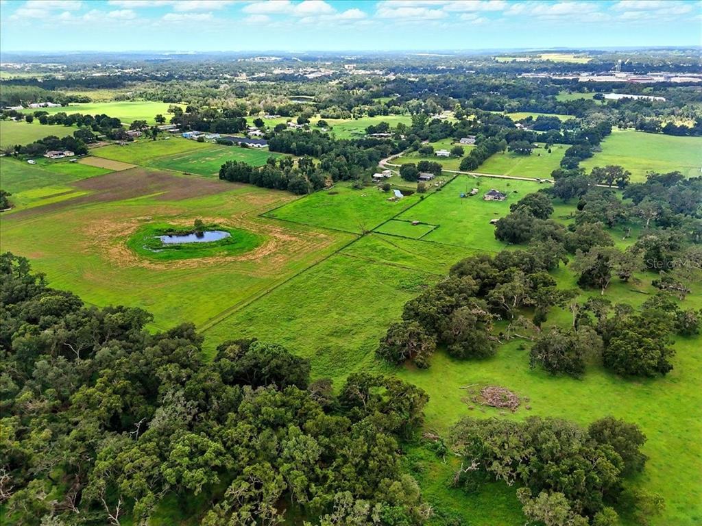 An aerial view shows a large, grassy pasture with a pond and scattered trees — 39410 SPARKMAN ROAD, DADE CITY, FL