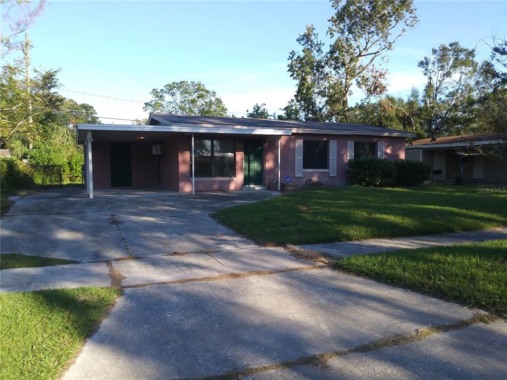 A single-story brick house features a front carport, a green door, and a concrete driveway — 2183 PATTERSON AVENUE, ORLANDO, FL