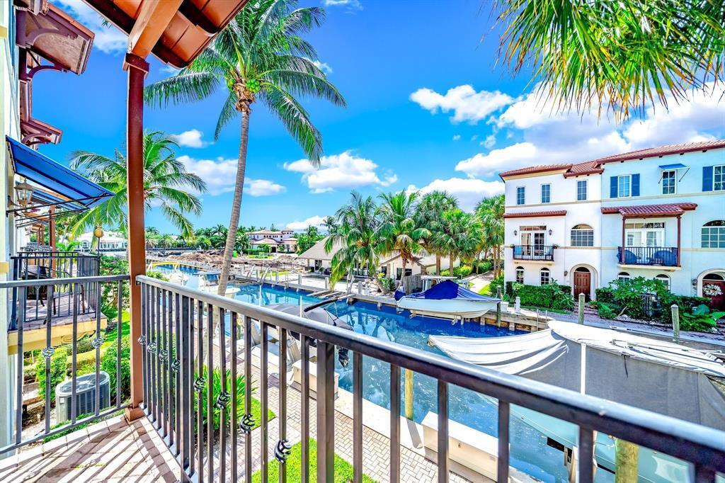 A balcony view overlooking a canal with docked boats and nearby residential buildings — 824 Virginia Garden Drive, Boynton Beach FL 33435, BOYNTON BEACH, FL